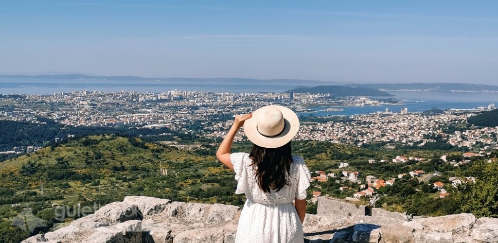 Woman standing on top of Klis fortress overlooking coastal city of Split in Croatia.